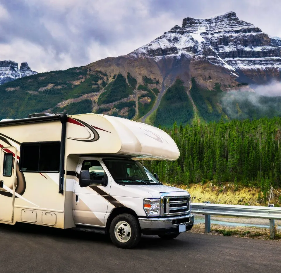 An image of a white truck driving on a road along the side of a mountain.