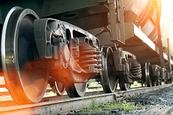 Close-up view of a train’s wheels and undercarriage on the railway tracks with sunlight shining through